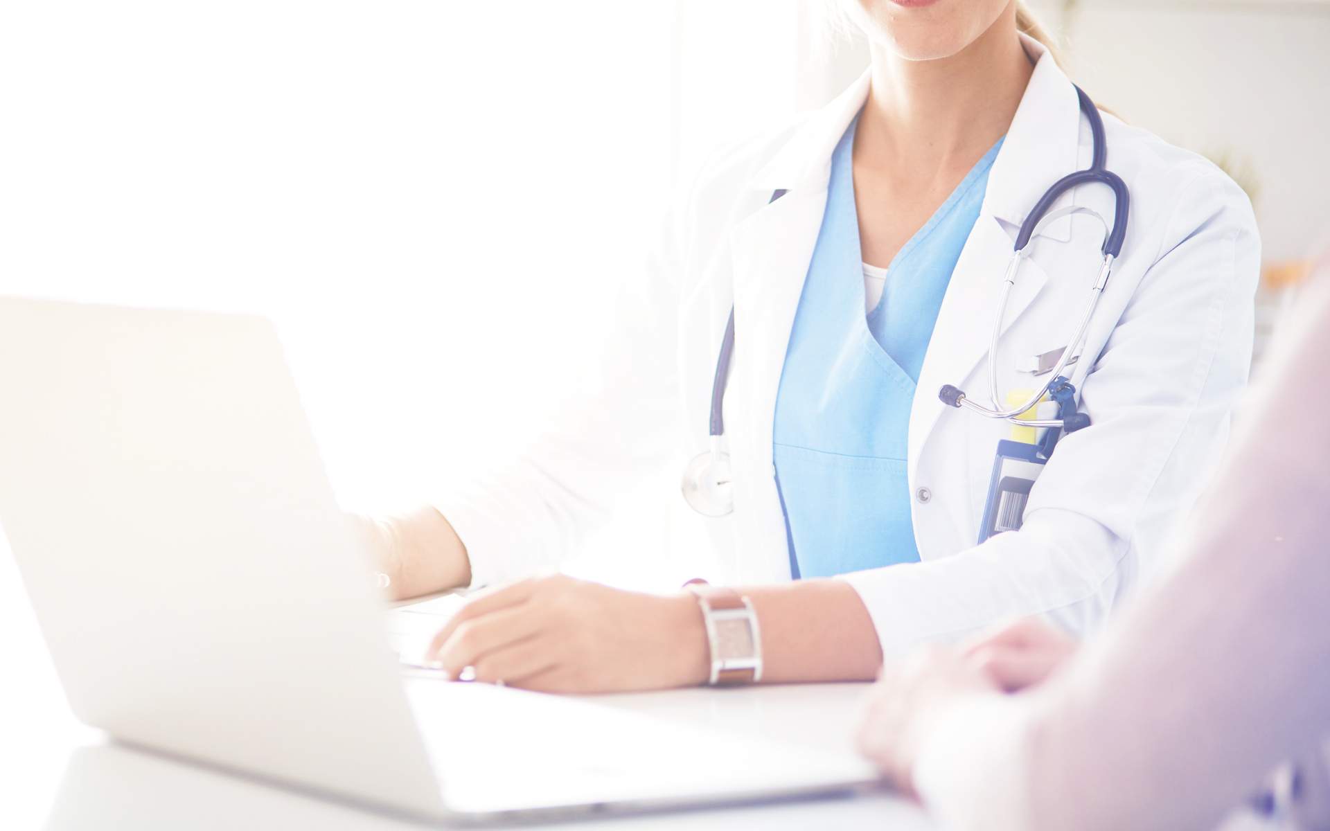 Image for 6 Common Health Insurance Terms Everyone Should Know. An image of a female doctor sitting at a desk with a laptop.